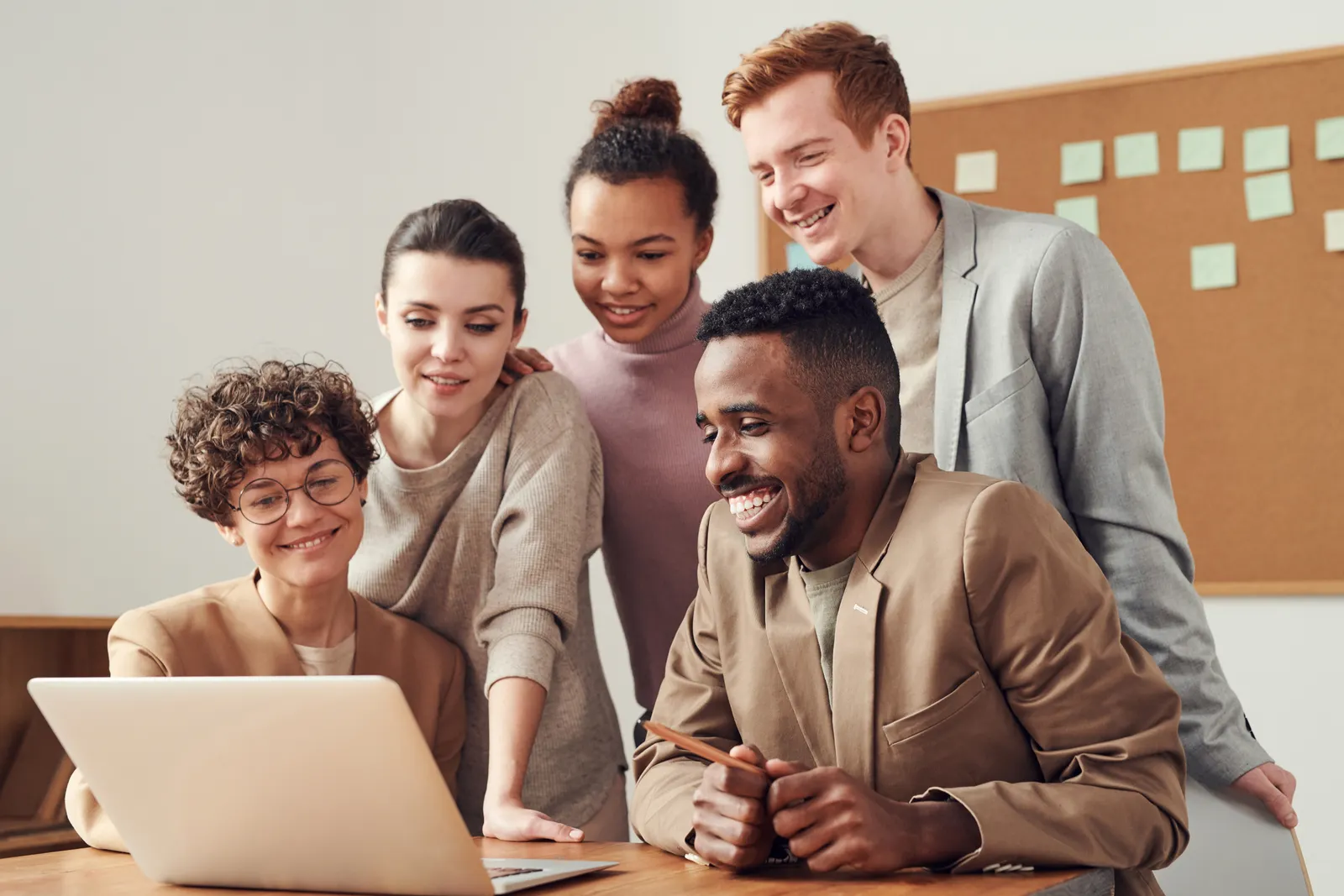 Grupo de profesionales reunidos alrededor de una computadora portátil conversando sobre un proyecto