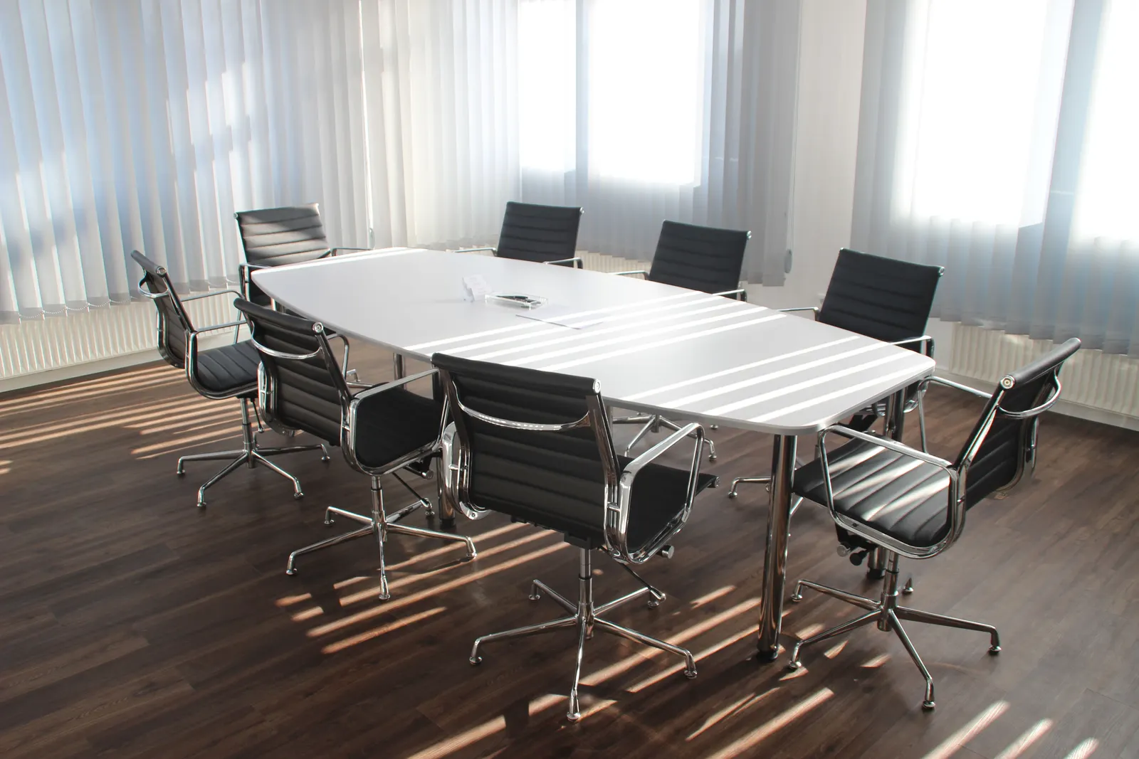 Sala de reuniones vacía con mesa larga y sillas, iluminada con luz natural